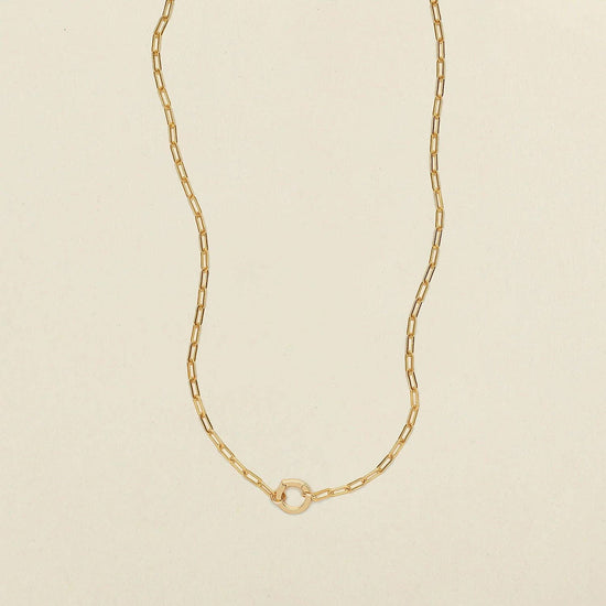 paperclip lock charm necklace on a beige background
