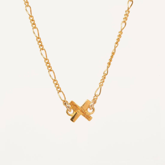 gold x charm pendant with woven details on a white background