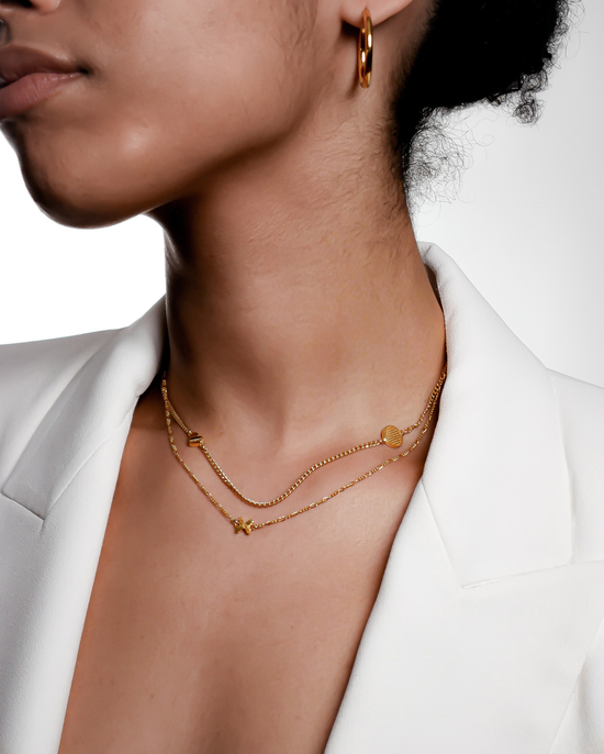 model wearing the woven x charm necklace layered with another gold pendant