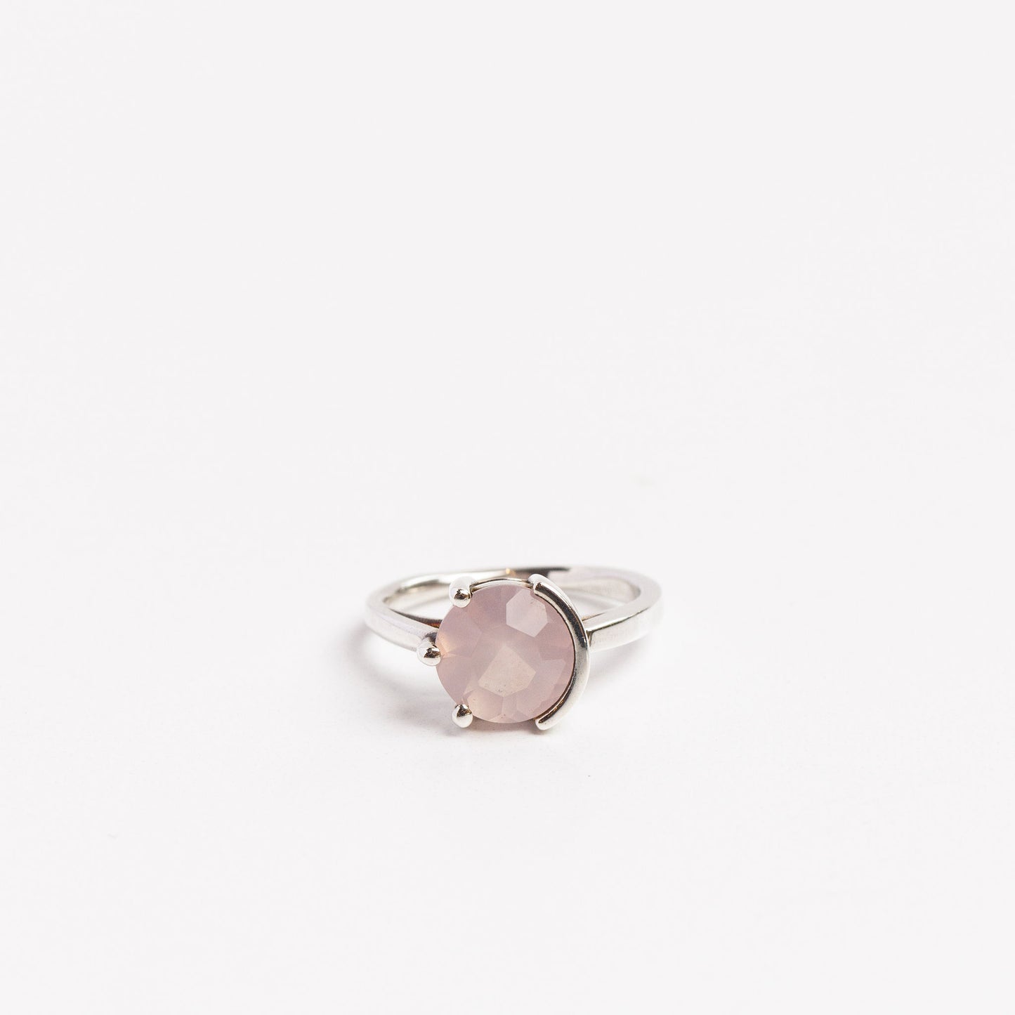 sterling silver ring with round rose quartz half prong half bezel set on a white background