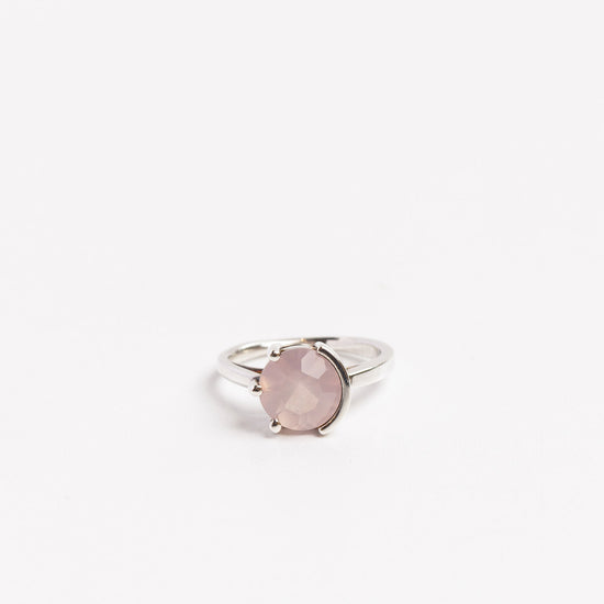 sterling silver ring with round rose quartz half prong half bezel set on a white background