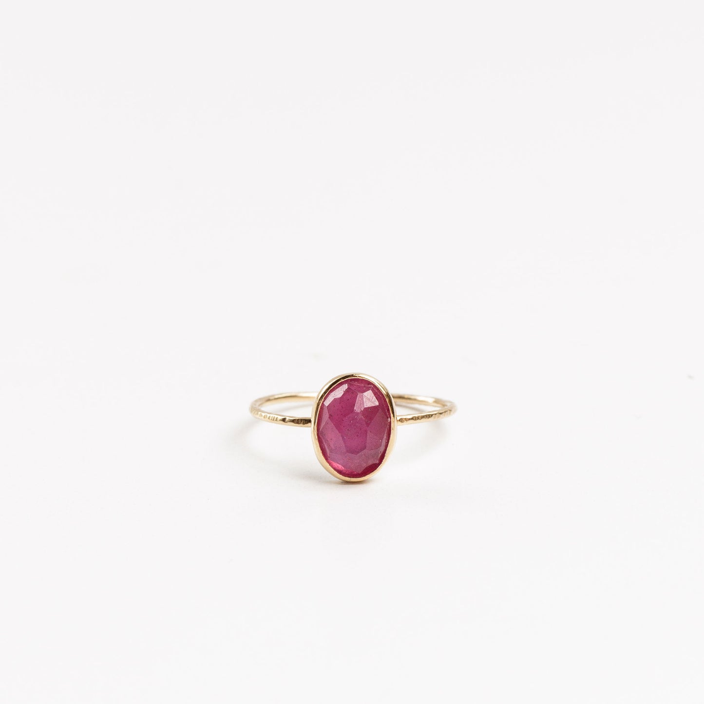 gold ring with oval hot pink tourmaline on a white background