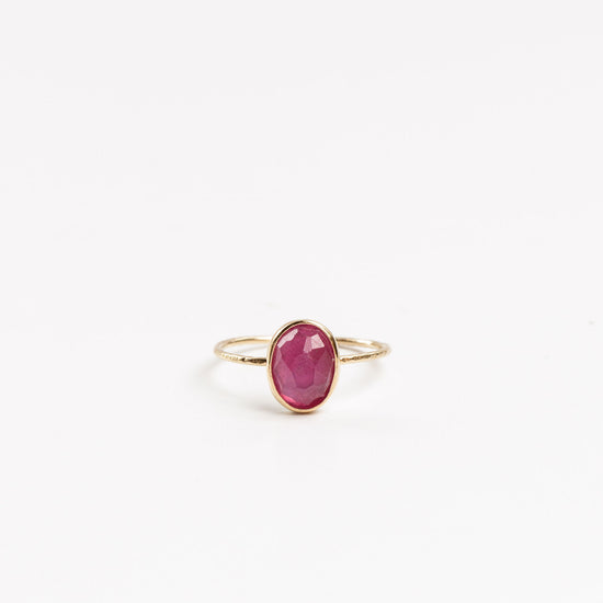 gold ring with oval hot pink tourmaline on a white background