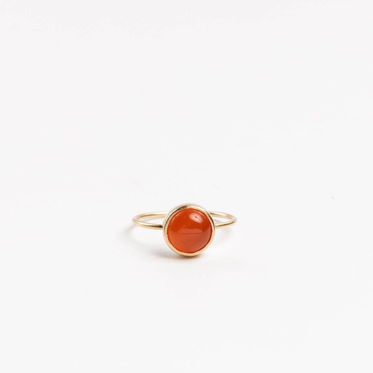 gold ring with a round carnelian cabochon on a white background