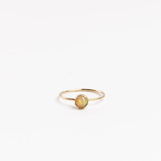 mini solitaire ring with round bezel set opal on a white background