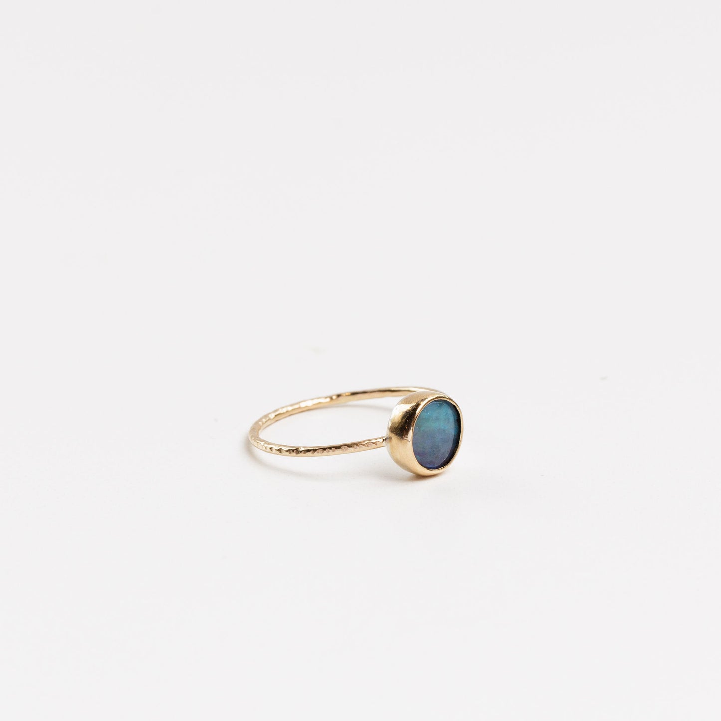 side view of the round blue opal ring on a white background