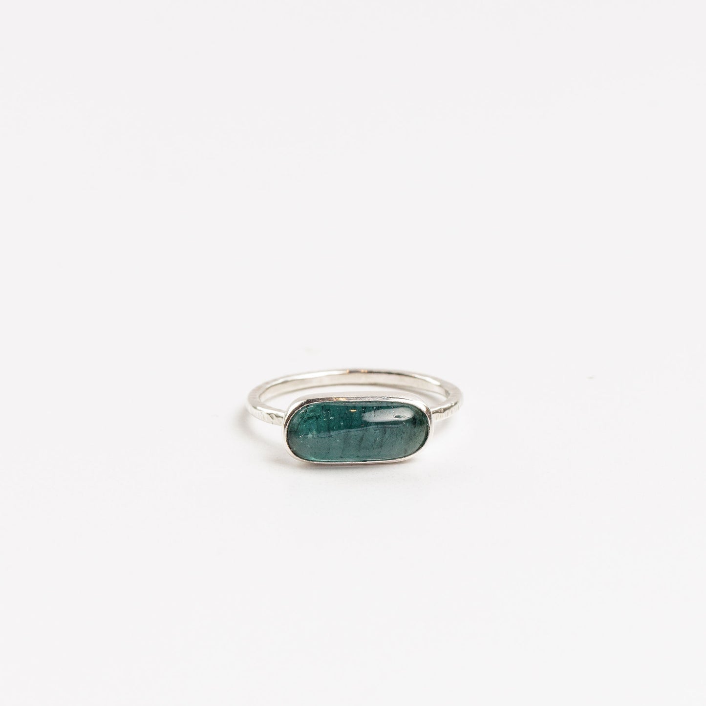 oval cabochon aquamarine bezel set in sterling silver ring on a white background