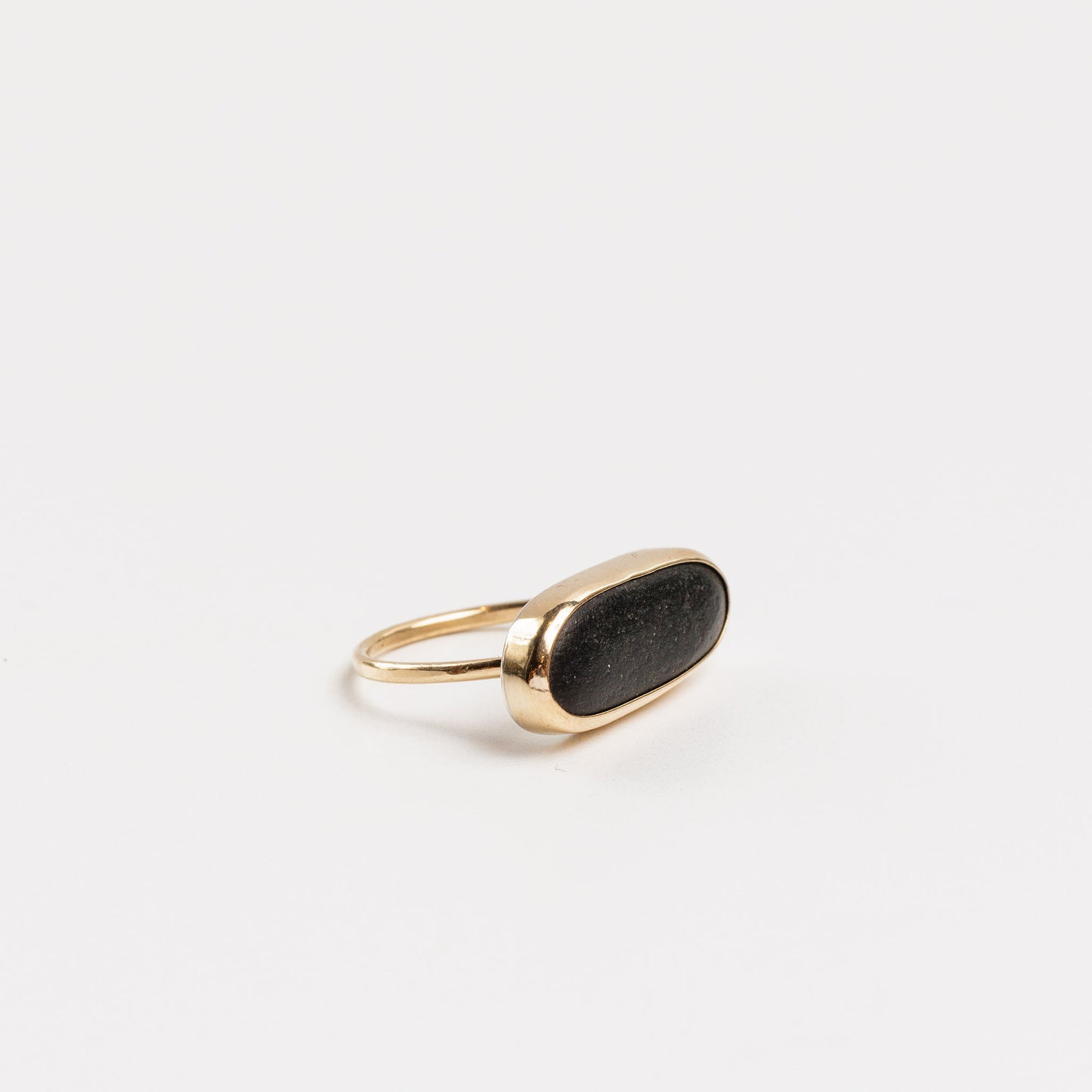 side view of the oval basalt solitaire ring on a white background