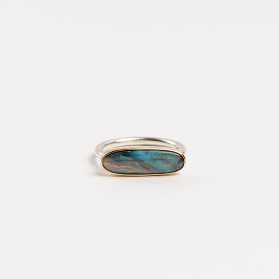 elongated oval opal bar ring in gold bezel and silver band on a white background