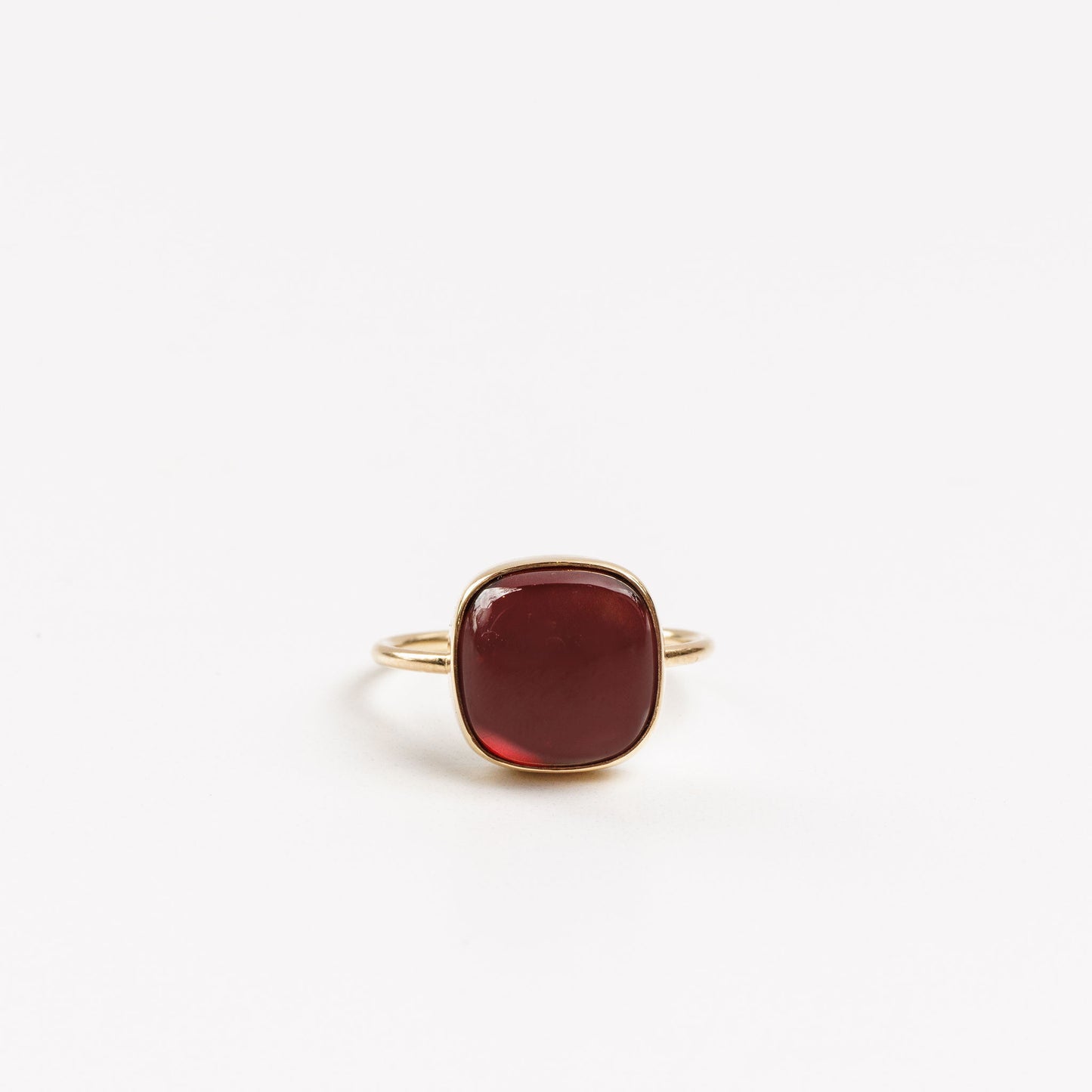 gold ring with a garnet cabochon bezel set on a white background