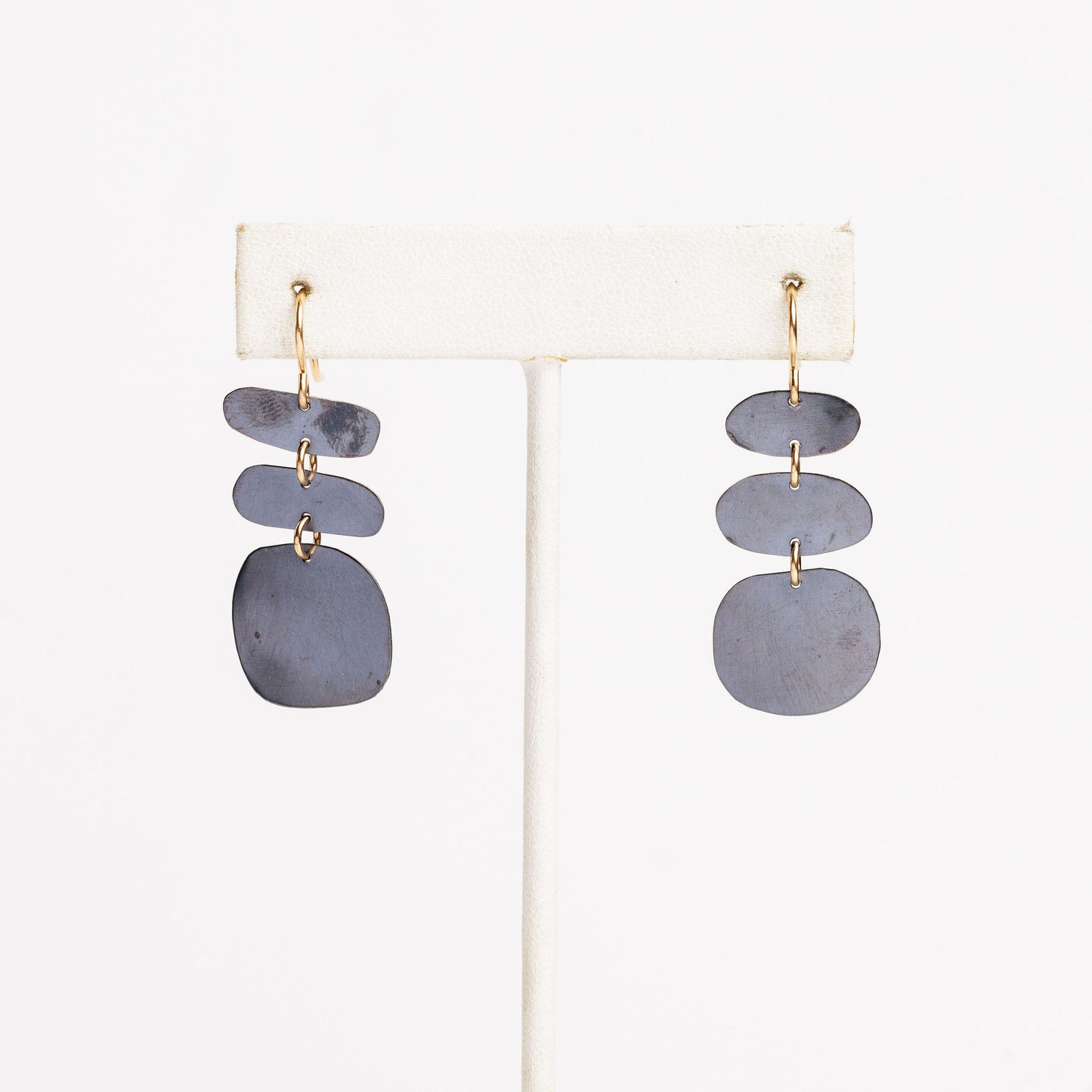 white earring stand with mismatched oxidized silver dandle earrings on a white background
