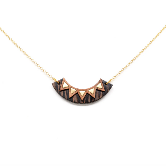 a two tone wooden arc necklace with brass triangle details and a gold plated brass chain spread out on a white background