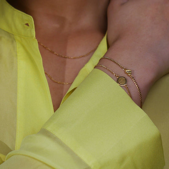 close up of a model wearing the love note charm bracelet with another chain bracelet