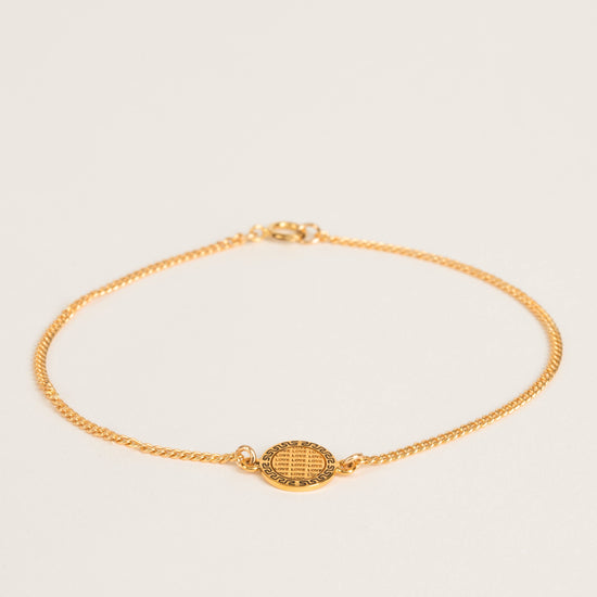 gold charm chain bracelet with love engraving on beige background