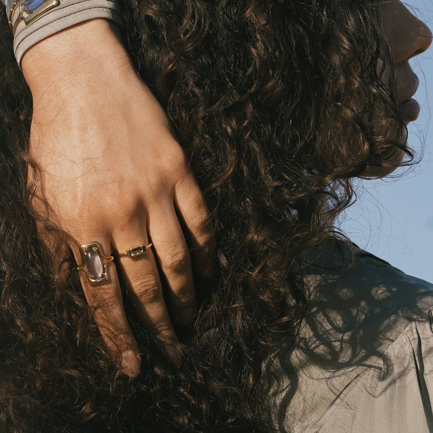 model wearing the blue walton ring on pointer finger and a gold band on middle with their hair on their head