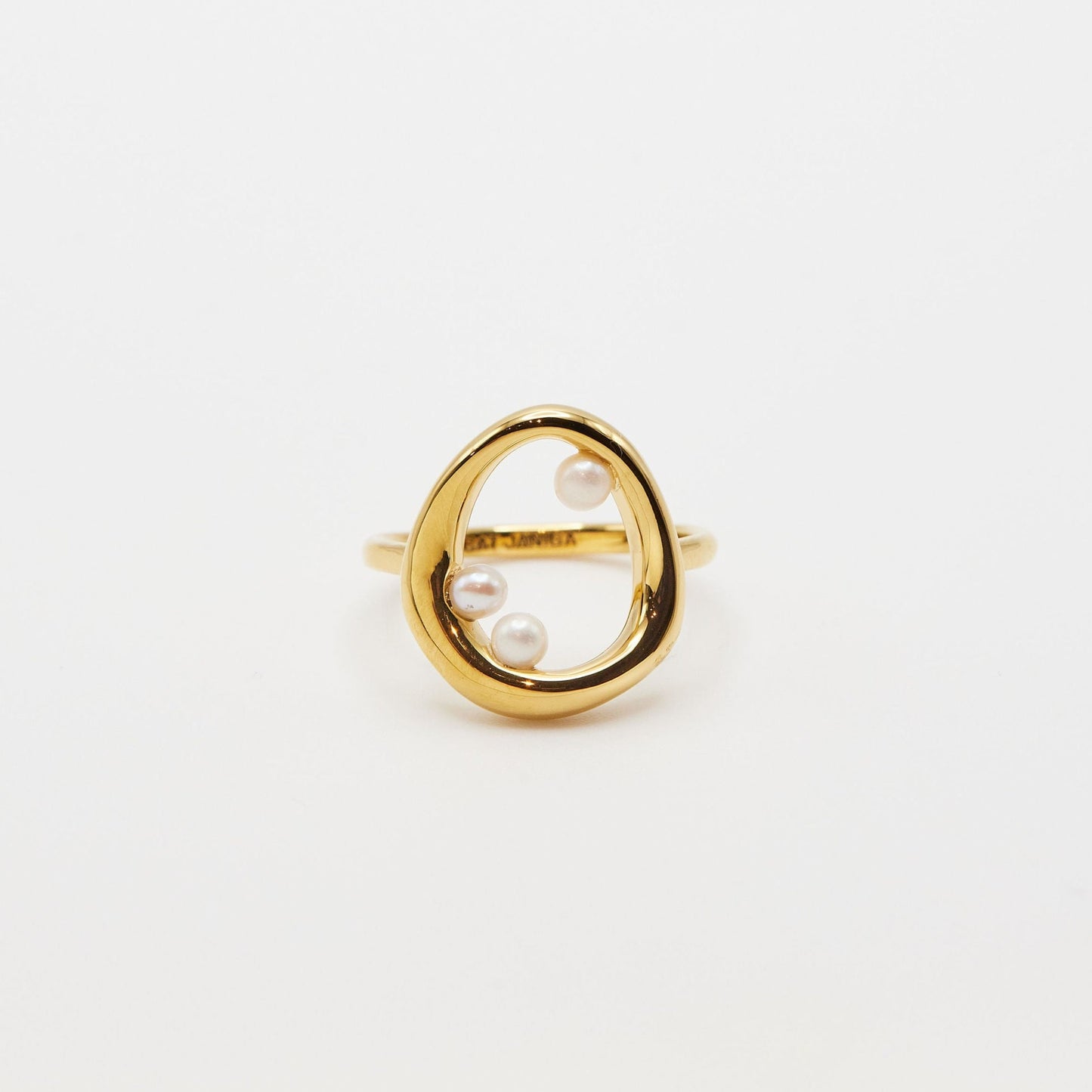 gold open circle ring with three small pearl accents on white background