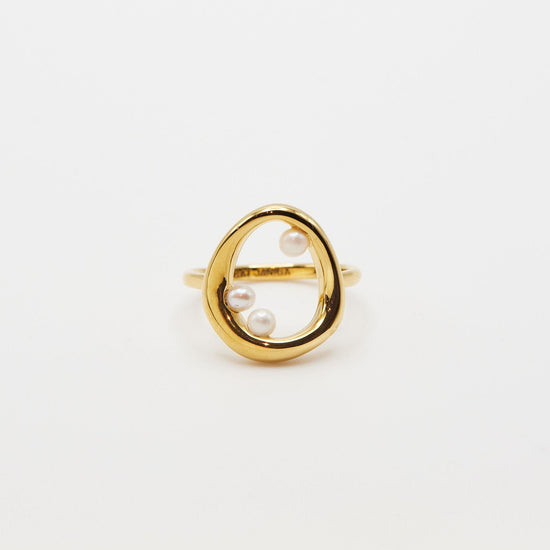 gold open circle ring with three small pearl accents on white background