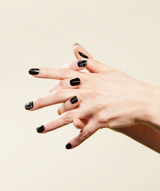 Hand modeling black with white line design nail wraps.