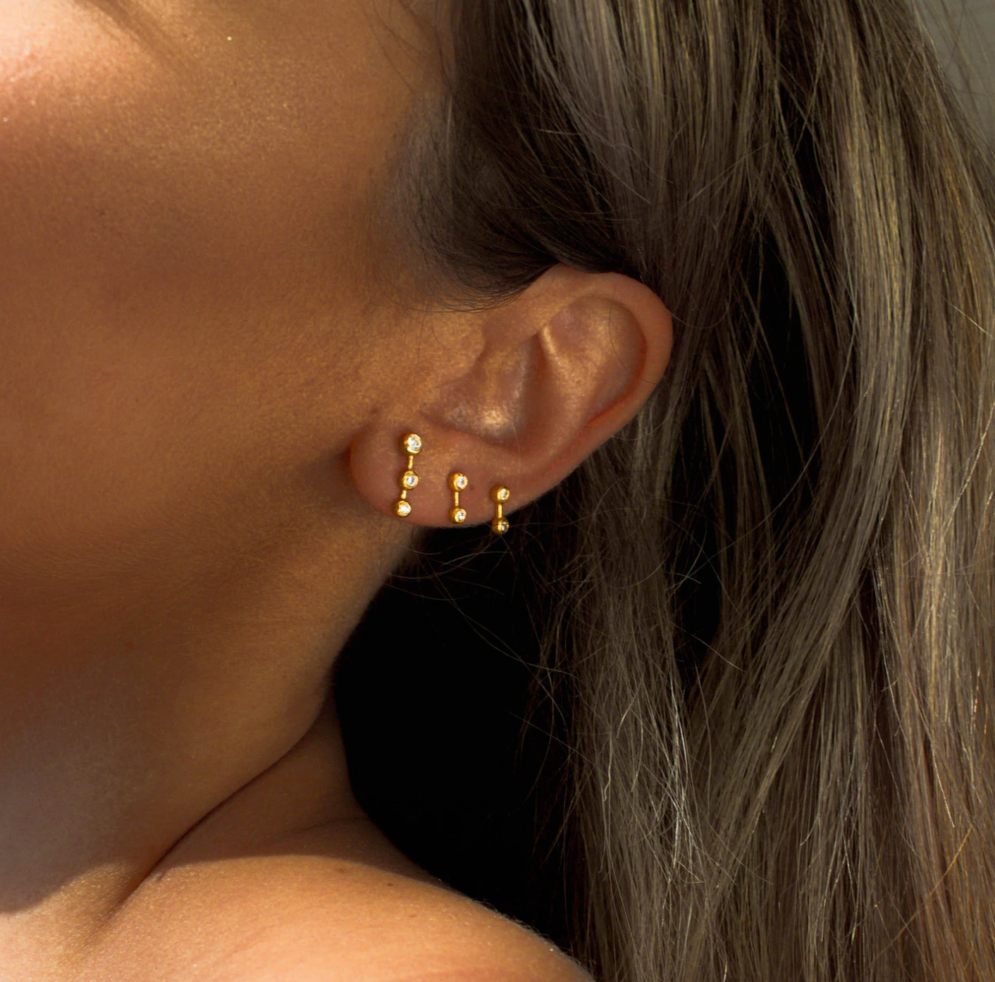 model wearing three star dust earrings.
