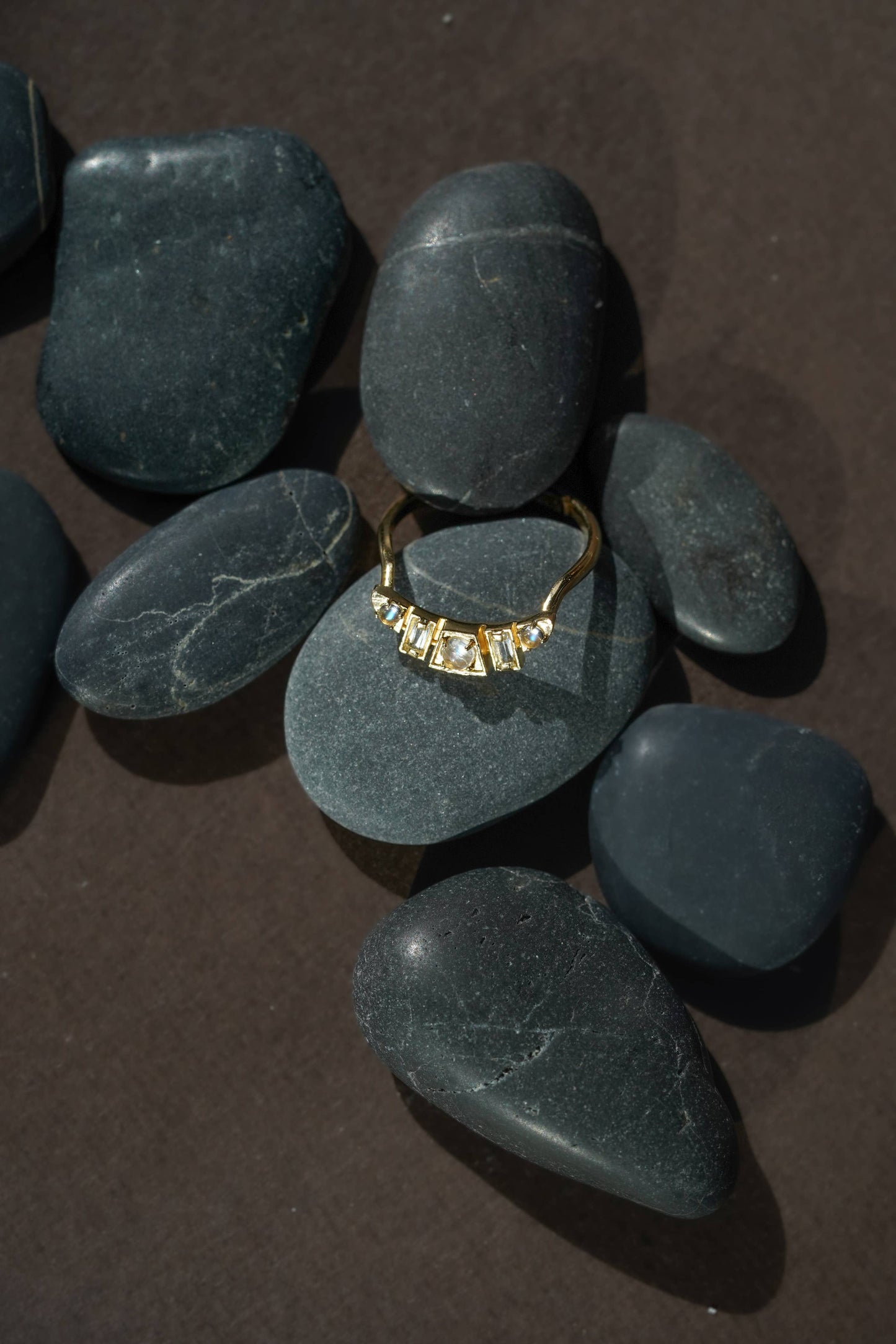 Gold ring on green stones with a dark brown background