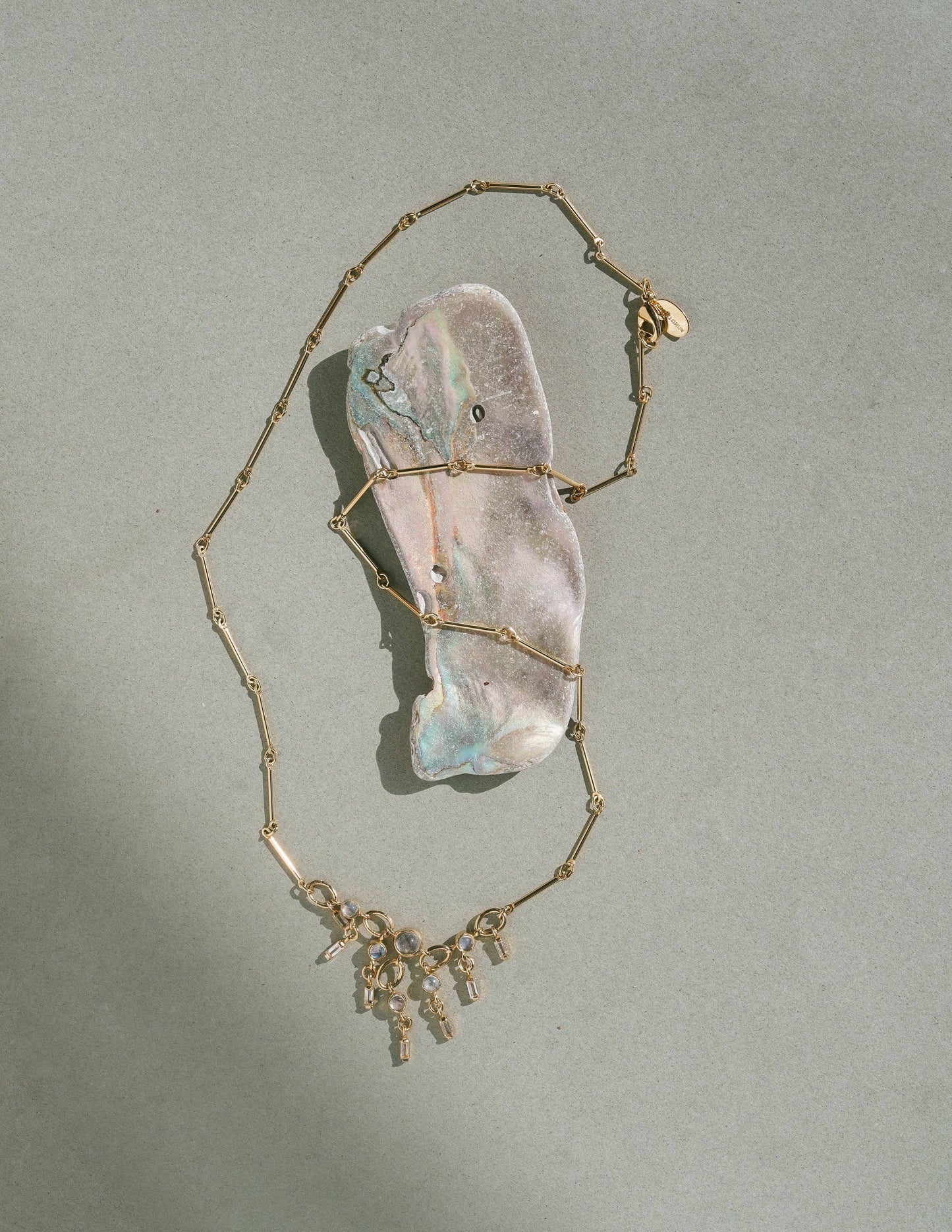 Necklace with gemstones sitting on a large stone on a light gray background