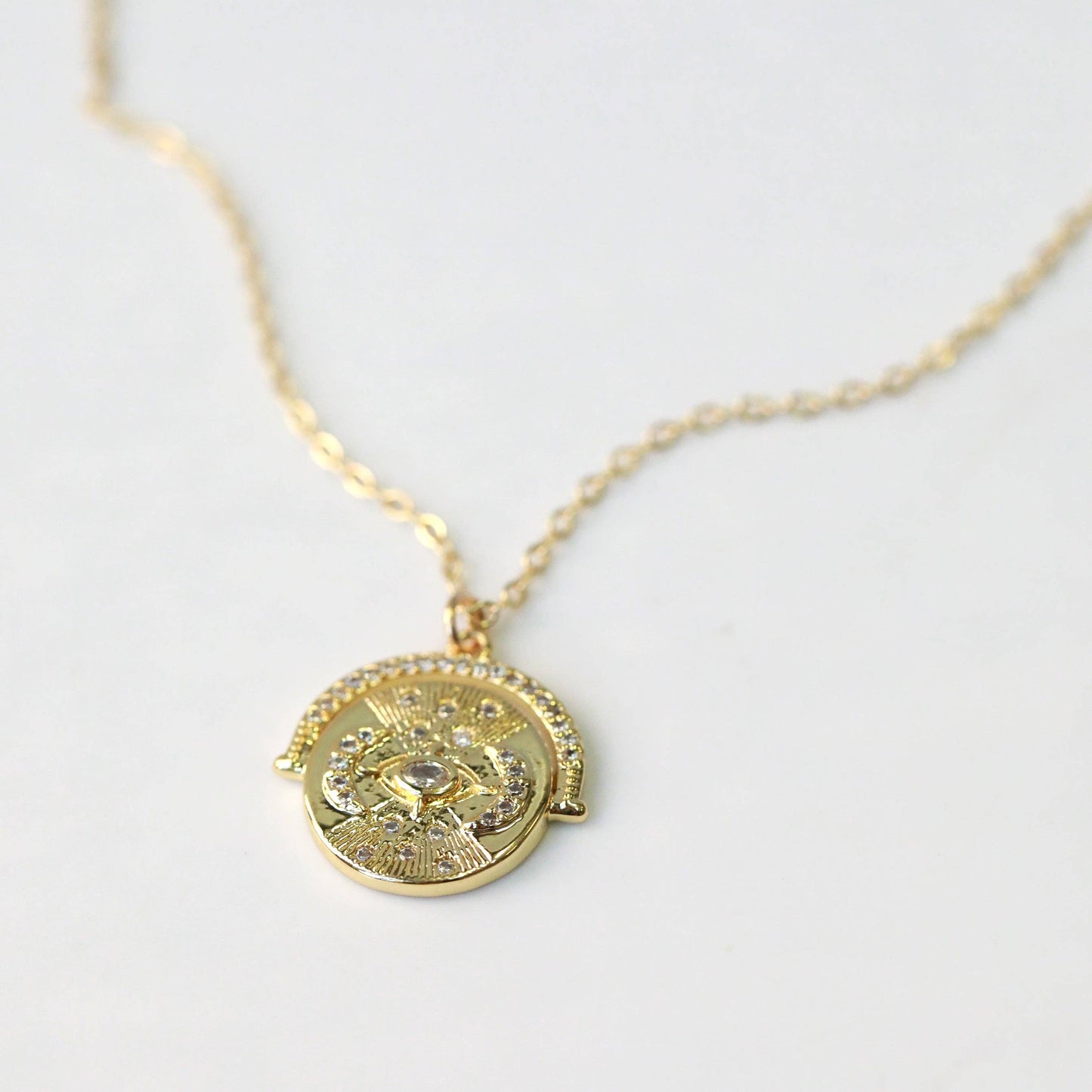 Gold necklace with a decorative pendant on a light gray background