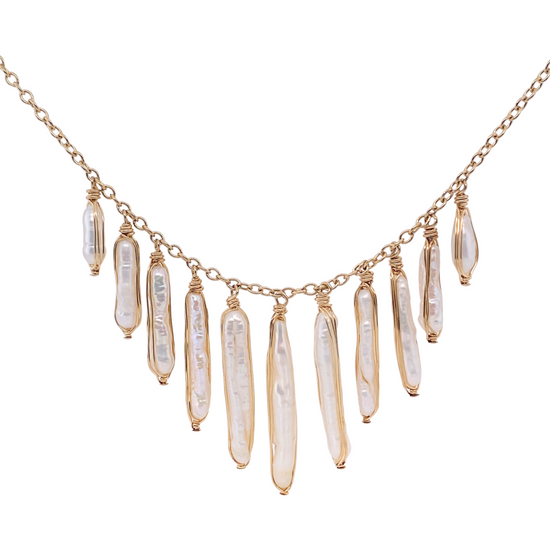 close up of gold chain necklace with varying sized pearl sticks on white background