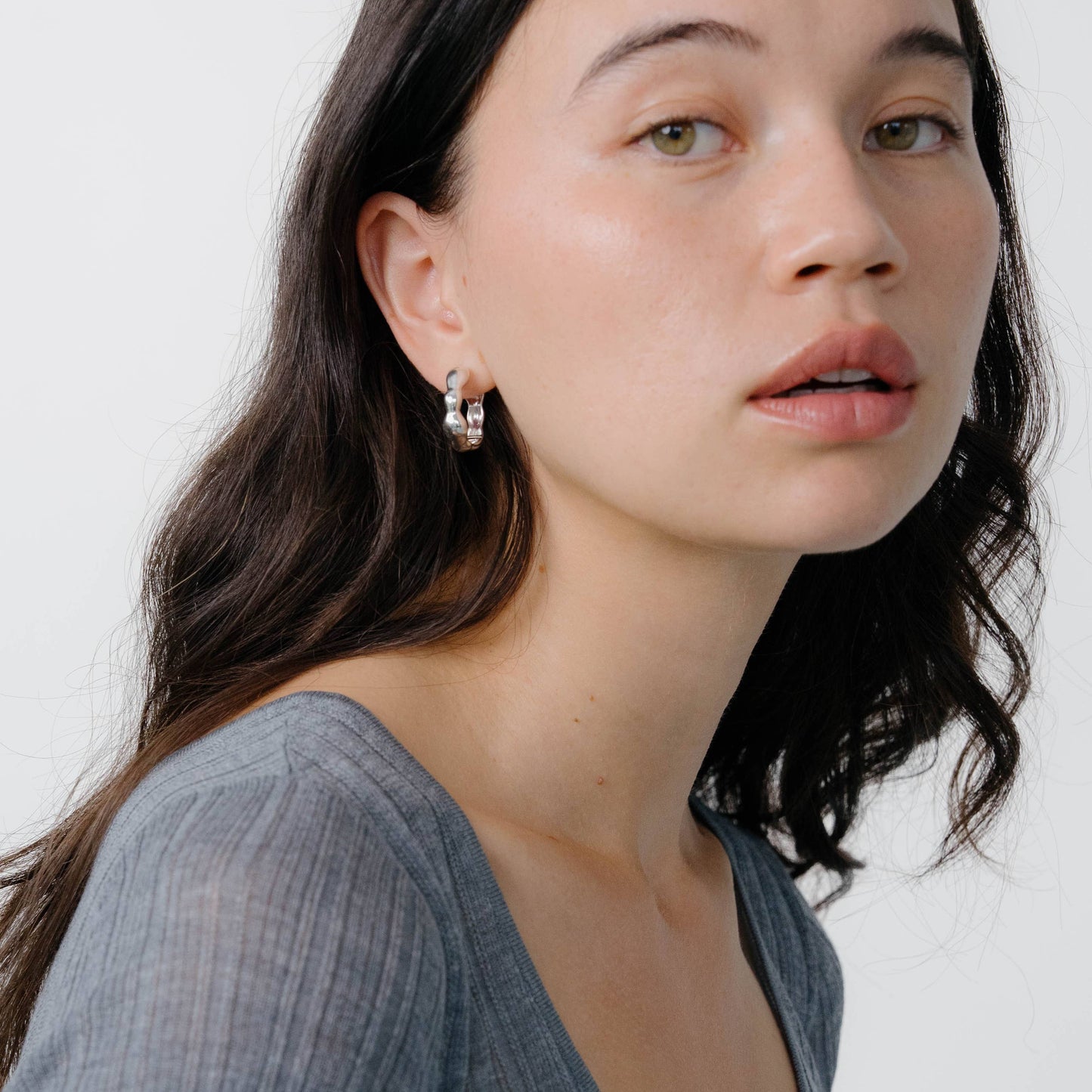 Woman wearing a gray top against a white background