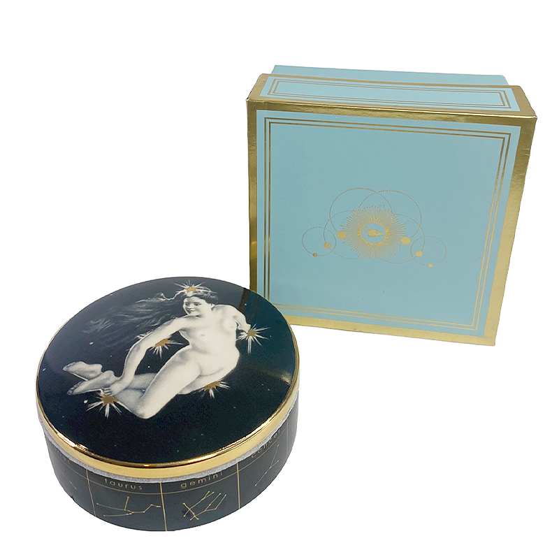 the astrological trinket dish next to a blue and gold box on a white background