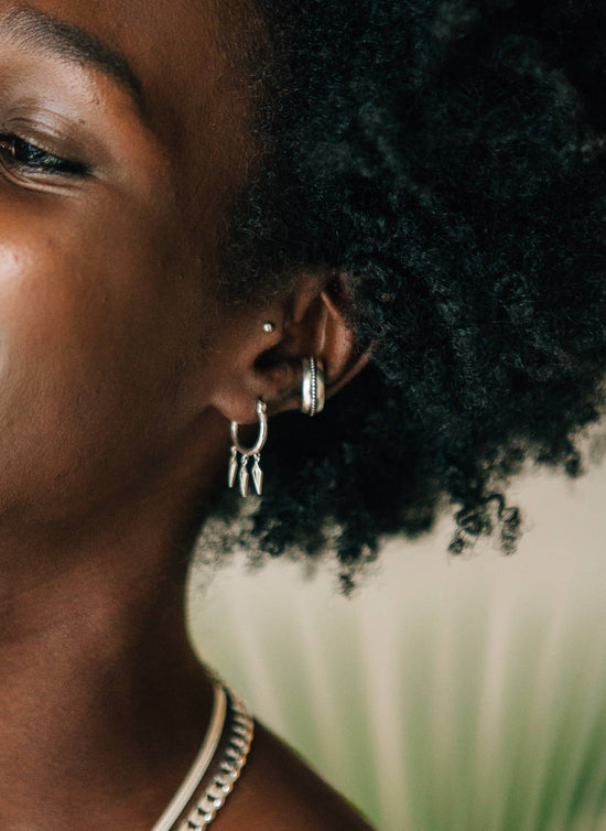 Close-up of a person wearing hoop earrings with a blurred background