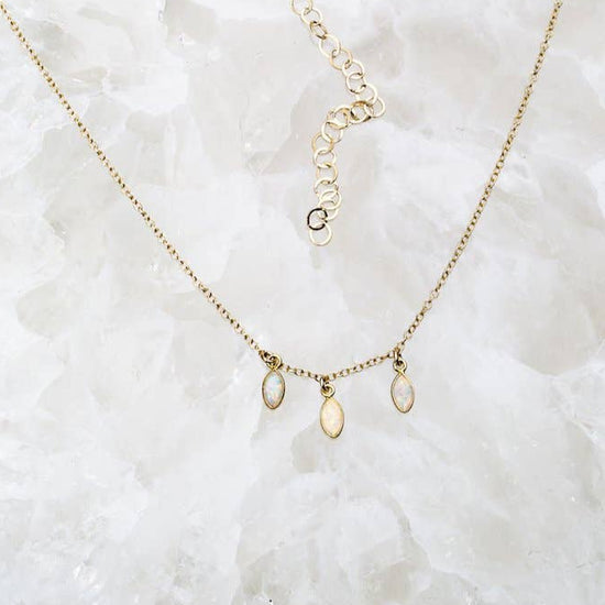 Gold necklace with small pendants on a textured white surface