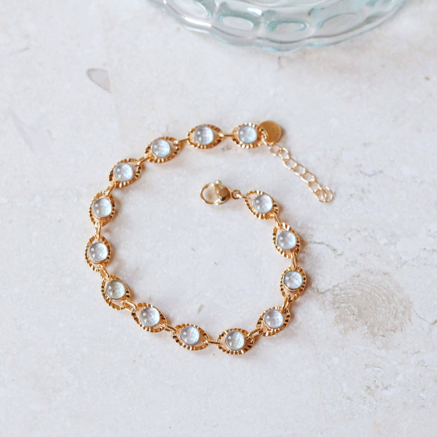 Gold bracelet with glass stones on a light background