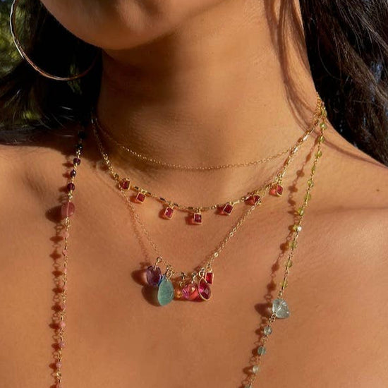 Close-up of a person wearing a yellow top and colorful beaded necklaces against a blue sky.