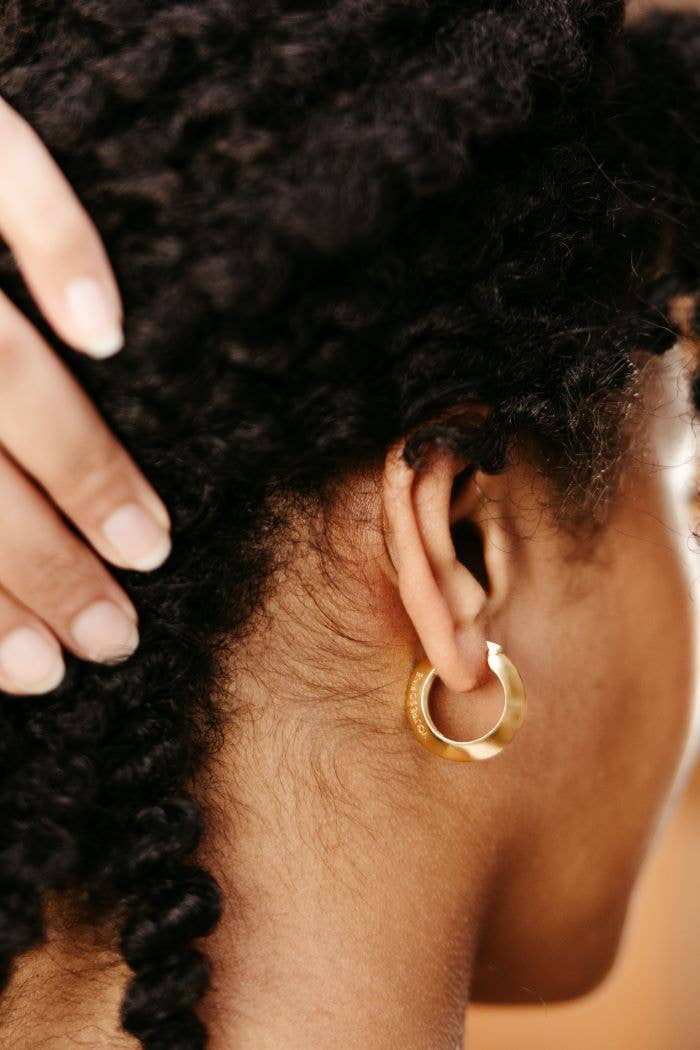 Close-up of a person's ear with a gold hoop earring 