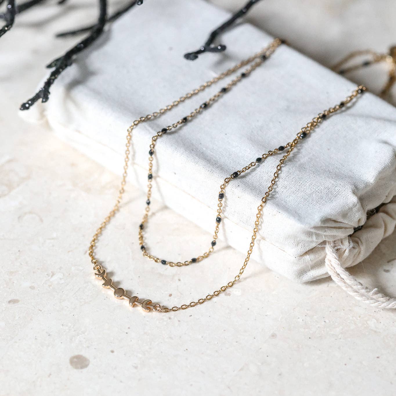 Gold chain necklace on a textured white surface