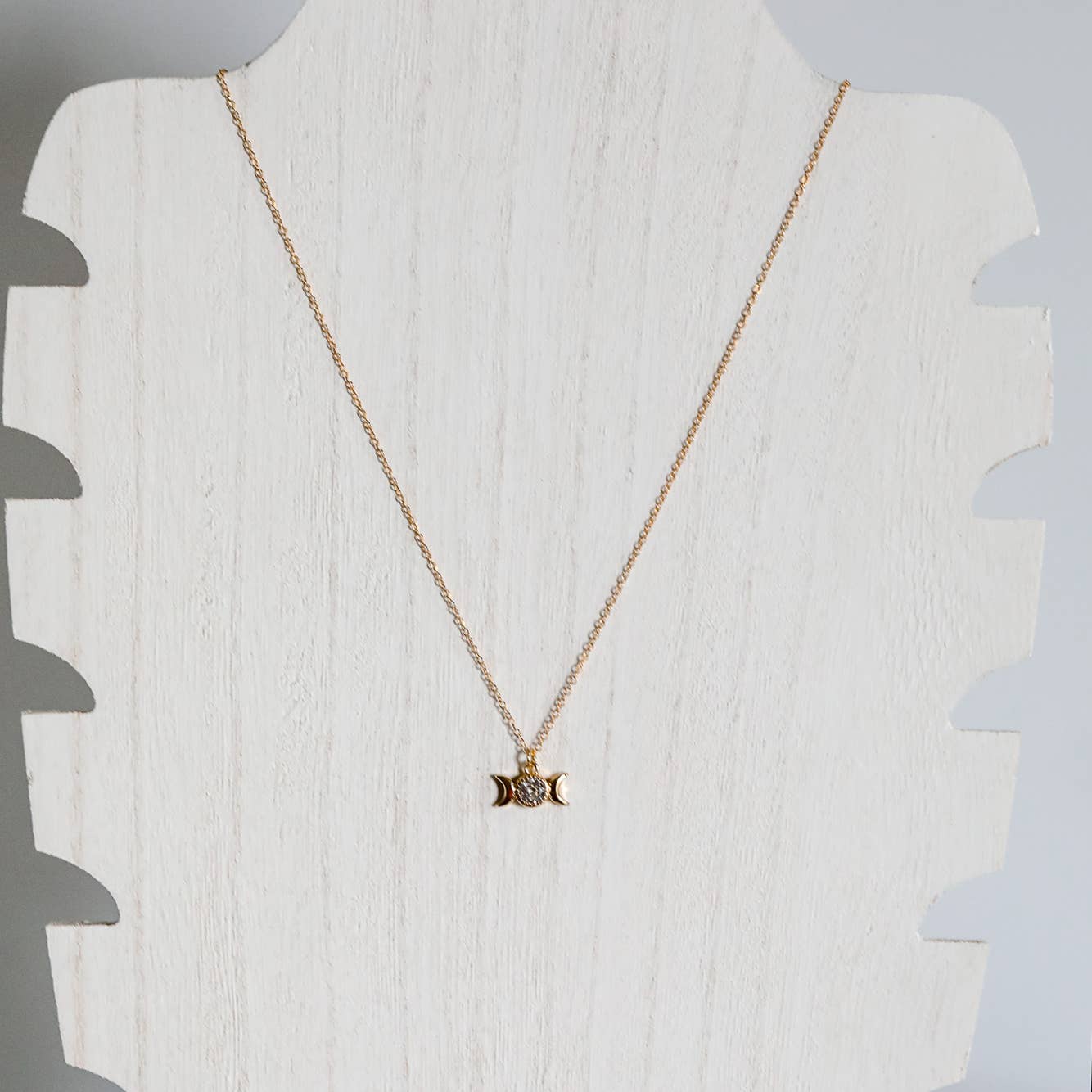 Gold necklace with a pendant on a mannequin bust against a white background