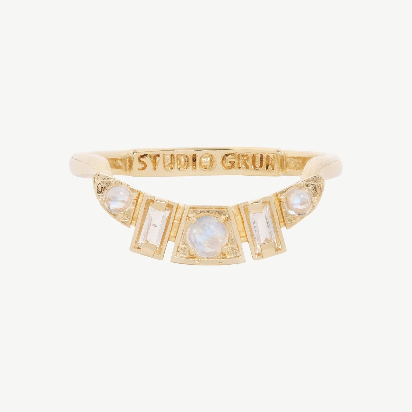 Gold ring with gemstones and 'Studio Grin' engraving on a white background