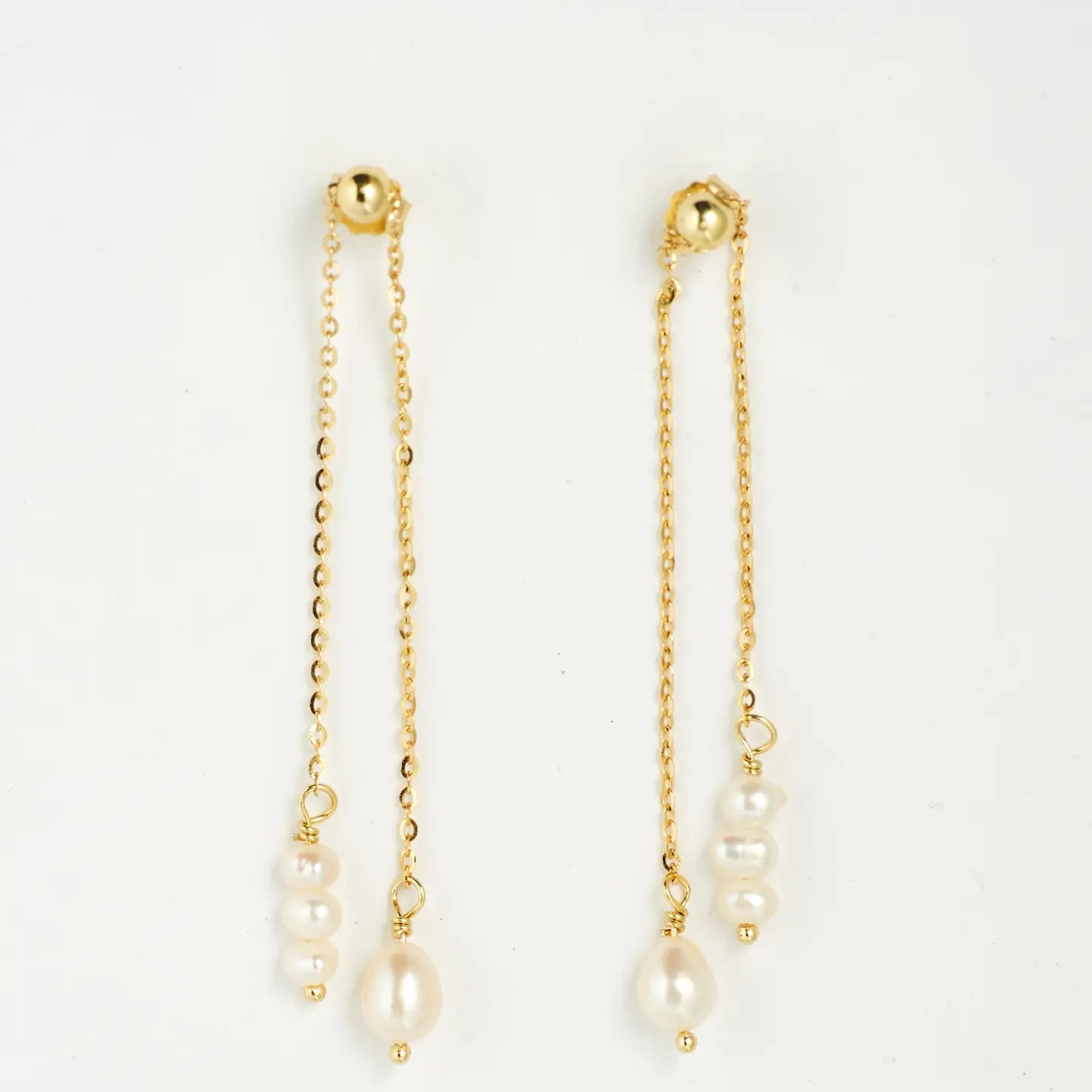 gold chain dangle earrings with pearl drops on a white background