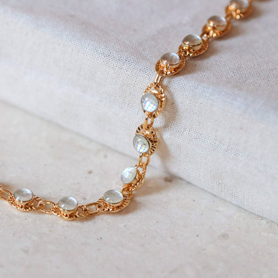 Gold bracelet with embedded stones on a light fabric background