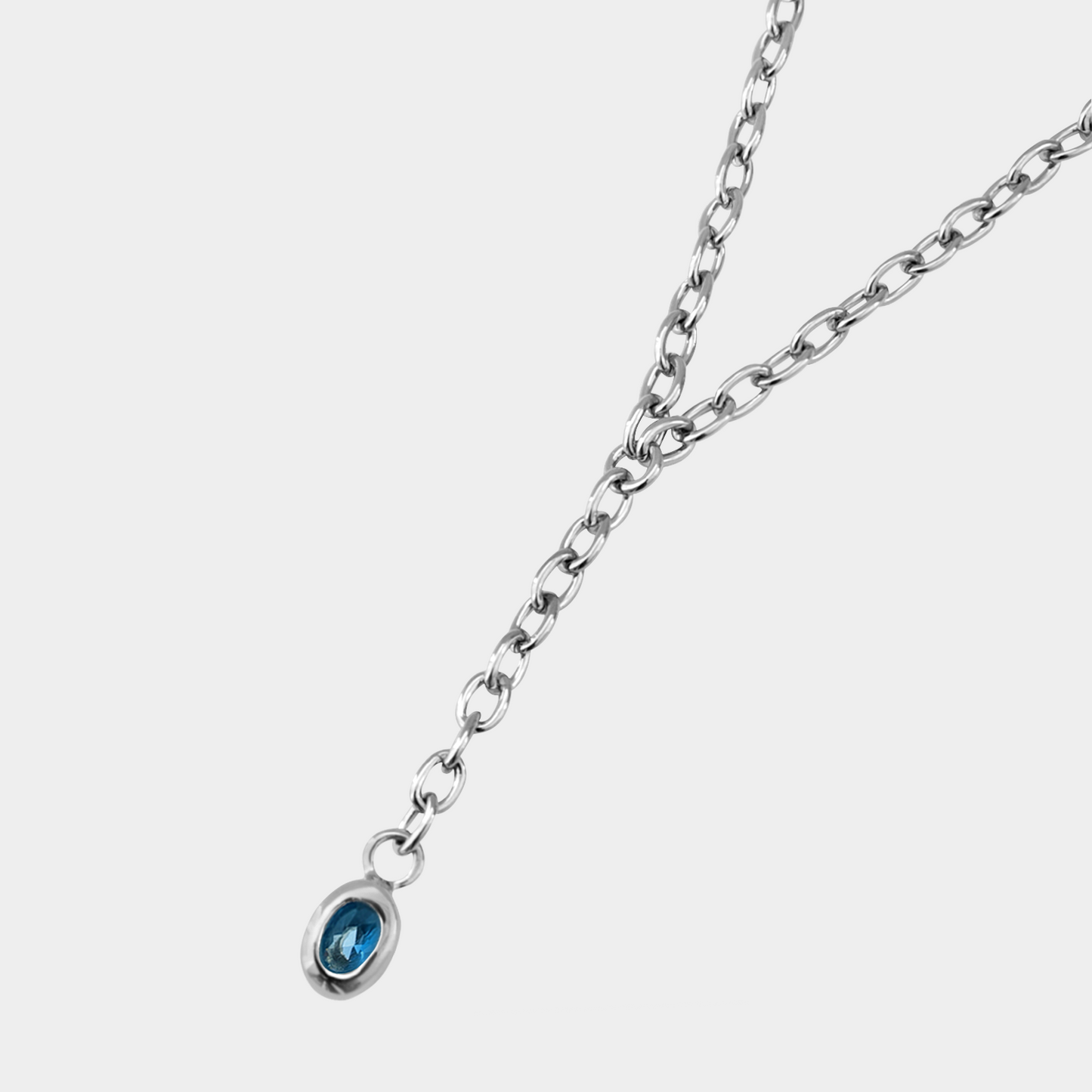 Silver necklace with a blue gemstone on a white background
