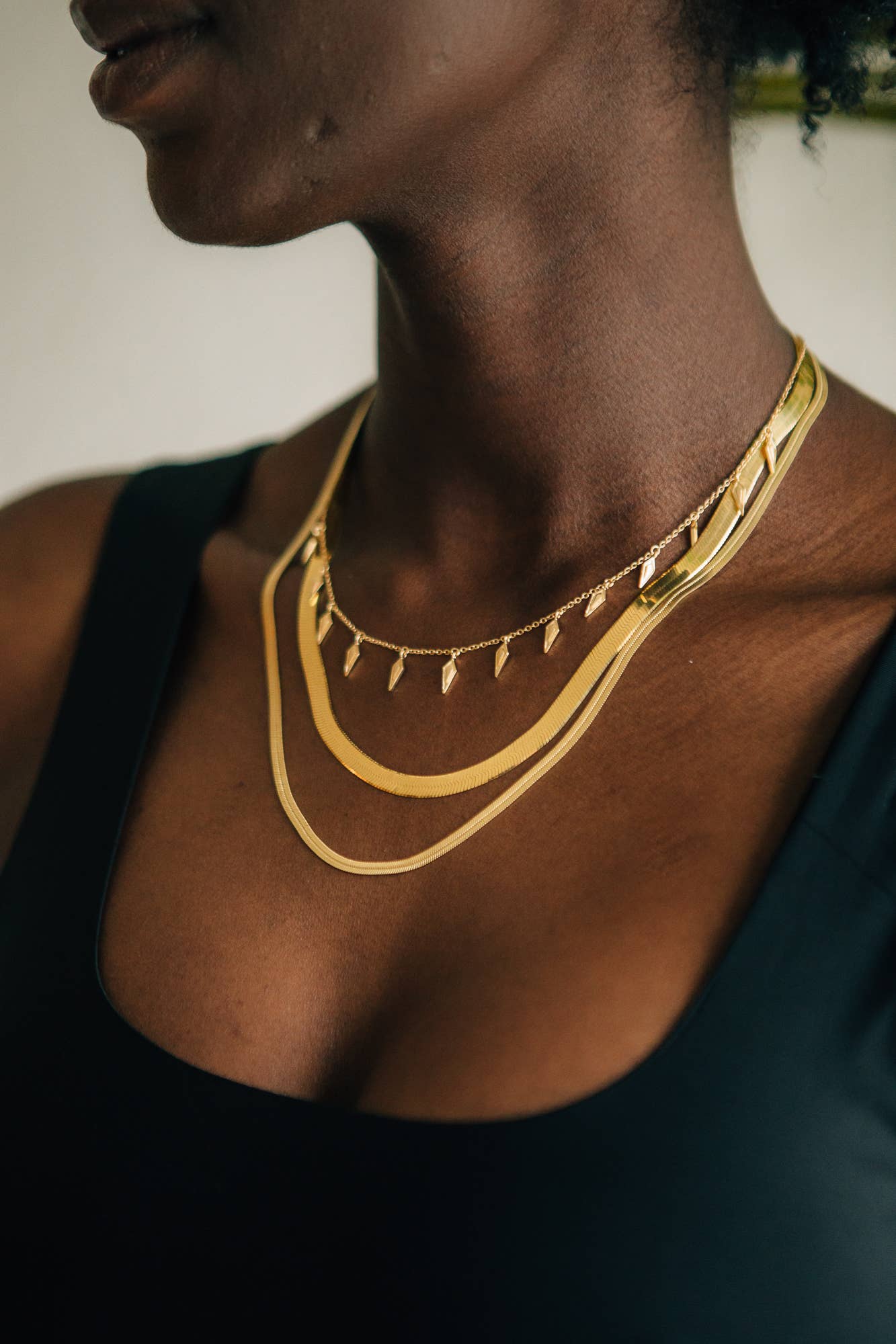Close-up of a person wearing a gold necklace with a blurred background