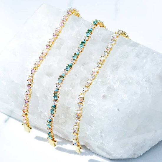 Gold bracelet with multicolored stones on a marble surface