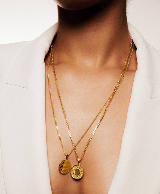 close up of a model wearing the love is love necklace layered with another coin necklace 