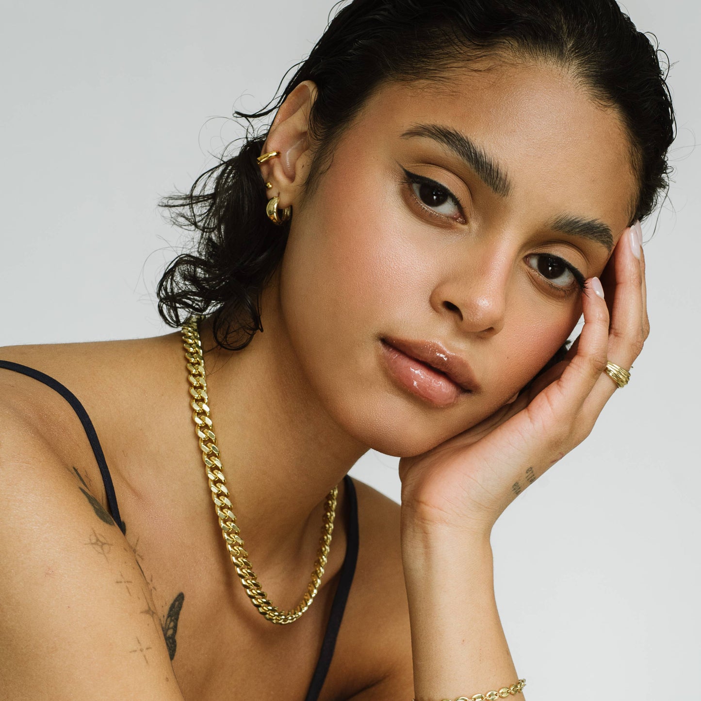 Woman wearing gold jewelry with a neutral background