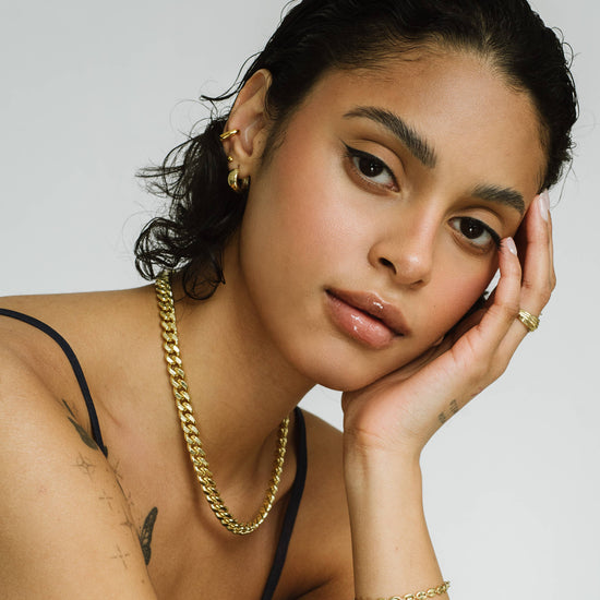 Woman wearing gold jewelry with a neutral background