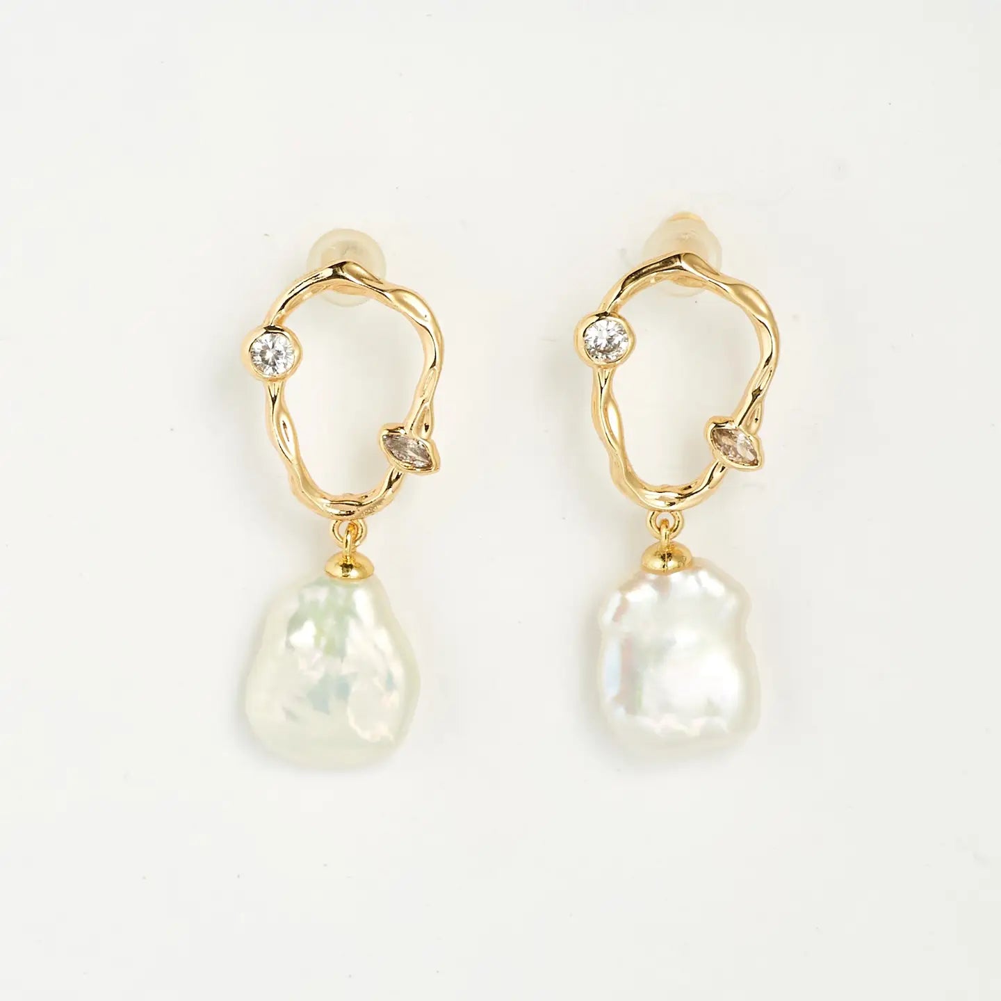 freeform gold earrings with pearl dangle and cubic zirconia details on a white background