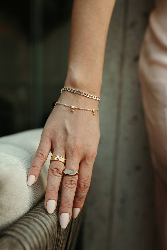 Hand with gold rings and bracelets on a blurred background