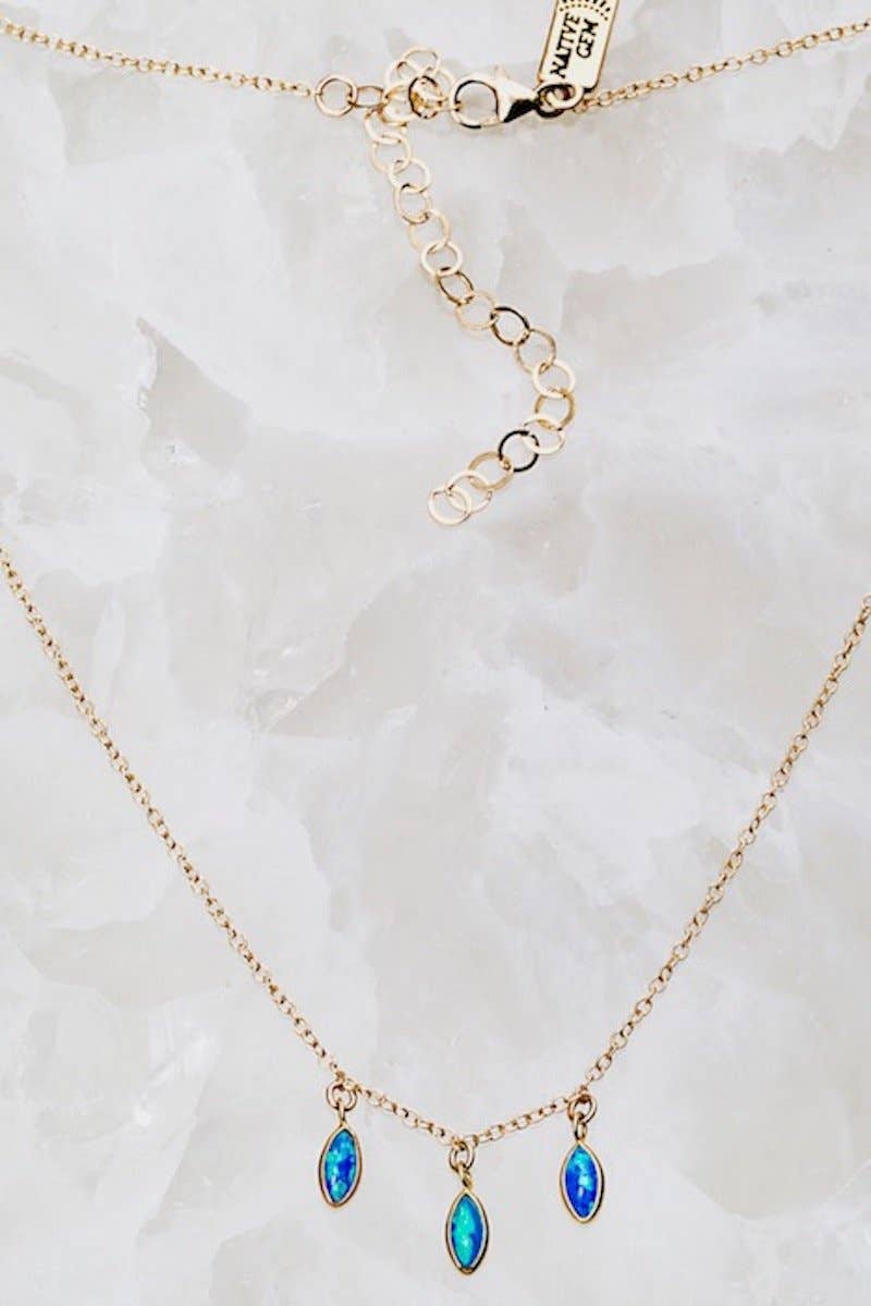 Gold necklace with blue gemstones on a marble background