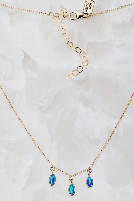 Gold necklace with blue gemstones on a marble background