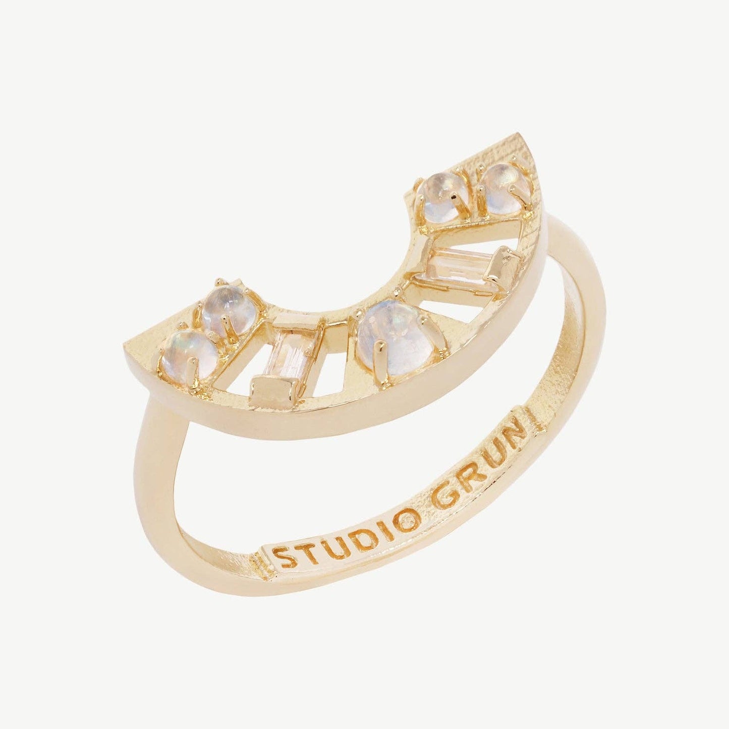 Gold arc ring with rainbow moonstone and topaz gemstones and 'Studio Grin' engraving on a white background